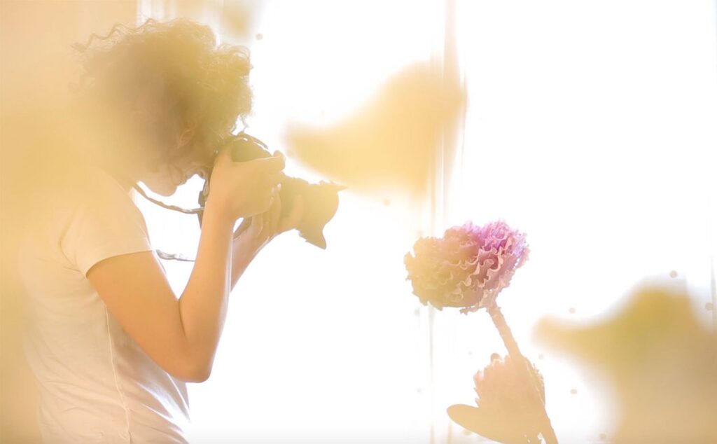 Fotografa che scatta una foto a un fiore. Arja Cajo